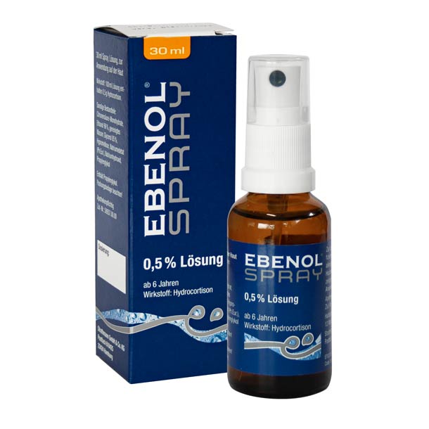 Eine 30-ml-Flasche Ebenol Spray 0,5% Lösung mit Hydrocortison neben ihrer blauen Verpackungsschachtel.